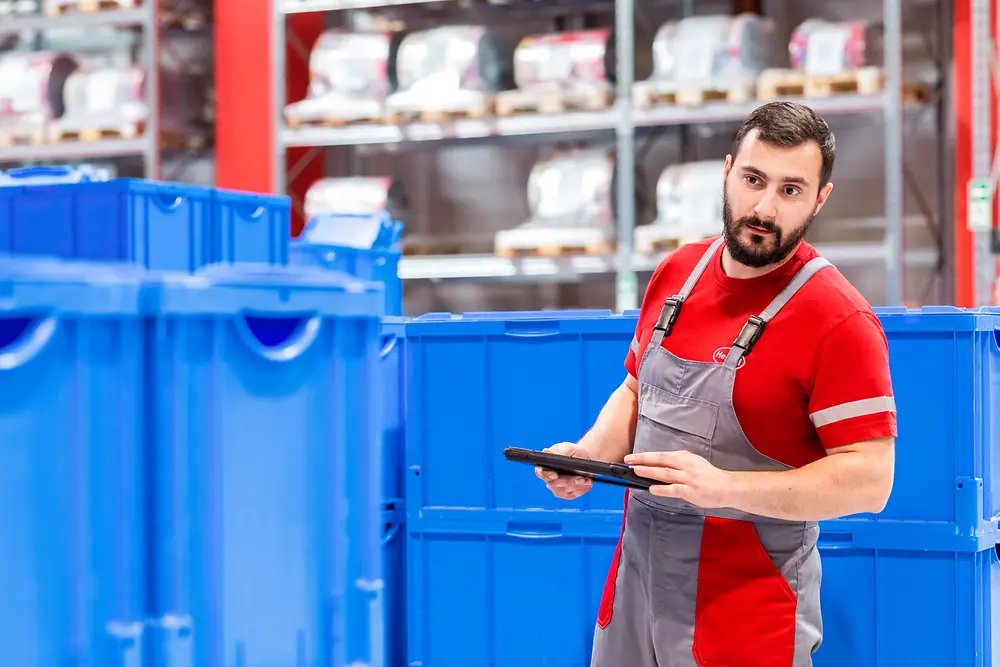 An employee is standing in the production plant checking that the processes are running as they should. 