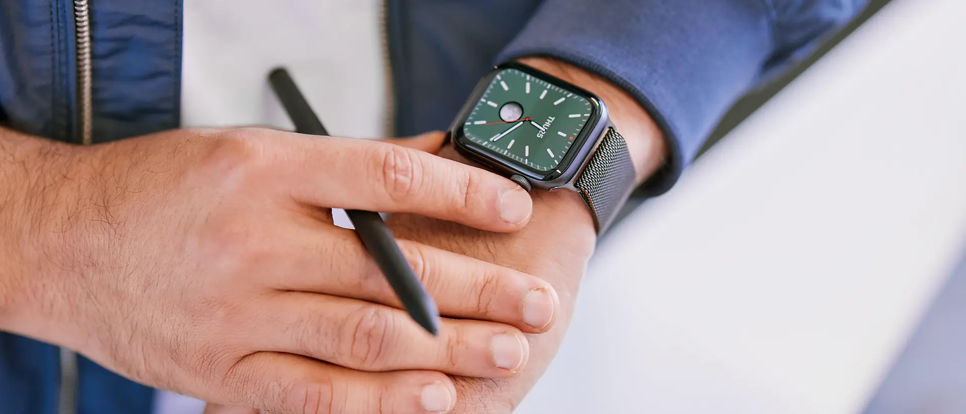A close-up of a man looking at a black smartwatch on his left wrist.